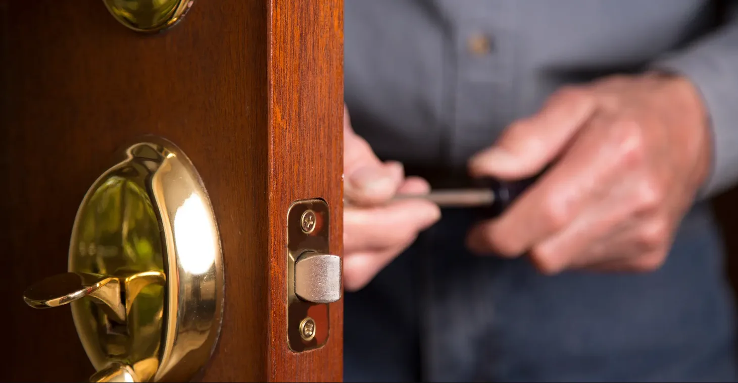 Professional lock repair service fixing worn cylinder mechanism on residential door